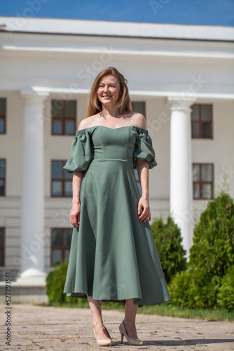 Full length portrait of a young beautiful red hair in green long dress