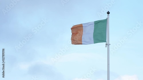National flag of the republic of Ireland waving in wind on blue sky background, Irish flag