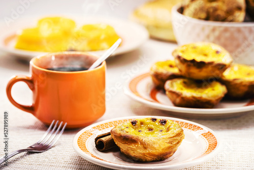 Traditional Portuguese dessert of pastel de nata, and bree de lis and bread in the background, served with coffee, typical Lisbon sweets