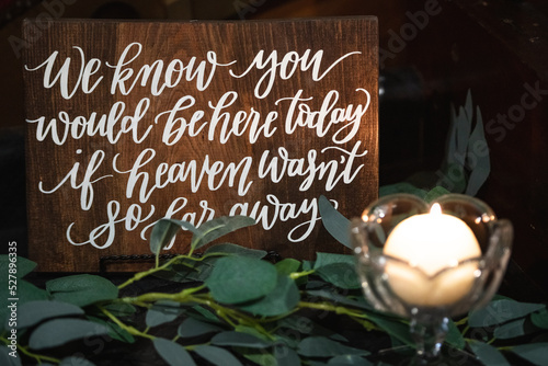 An in memoriam table with eucalyptus leaves spread around a lit candle with a sign that reads 