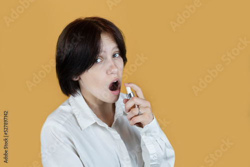 The girl uses a breath freshener, sprays an odorous liquid into her open mouth, maybe it's time for the girl to go to the dentist to treat her teeth in time.