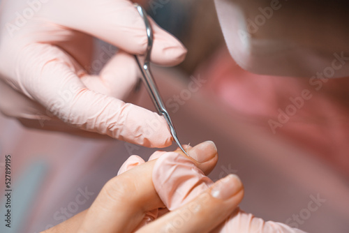 Manicure salon master removes cuticles with nail scissors. Woman getting nail manicure. Professional manicure in beauty salon. Hygiene and care for hands. Beauty industry concept