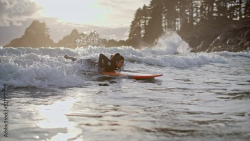 Surf girl catches wave at picturesque tofino beach during sunset