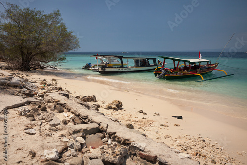 Two traditional Indonesian fishing boats reconverted in tourist boats moored on a Gili Meno beach photo