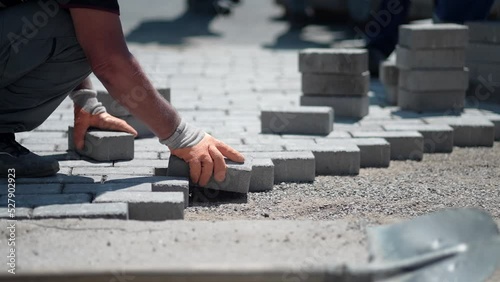 The master in yellow gloves lays paving stones in layers, slow motion
