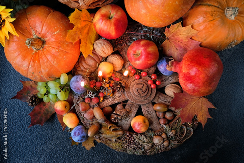 Wiccan altar for Mabon sabbat. fruits, pumpkins, candles, nuts, wheel of the year on black background. pagan, Wiccan traditions. Witchcraft, esoteric spiritual ritual. top view photo