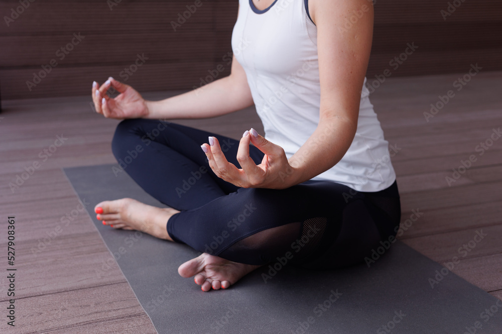 Beautiful strong muscular woman doing stretching on mat on terrace outdoors. Healthy young adult girl in  sportswear stretch alone. Fit thin gimnast doing yoga, training on mat	