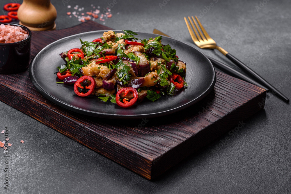 A salad of baked aubergine, sweet pepper, garlic, zucchini and parsley in a black plate