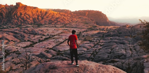 Rear view of man on edge of cliff, surrounded by mountains. An image from Jabal Qahar, Saudi Arabia. photo