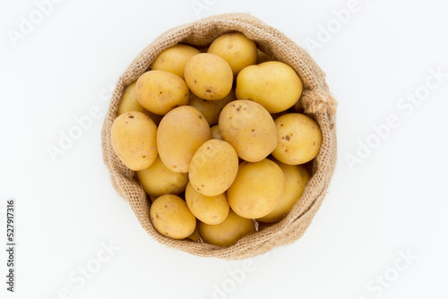 Sack of fresh raw potatoes on wooden background, top view