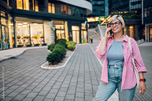 Plus size woman with pixie hair using smartphone in the city street.