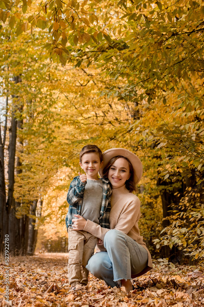 Portrait of Mother and son walking outdoors on a sunny autumn day. The family is dressed in autumn clothes. Happy together Portrait of Mother and son walking outdoors on a sunny autumn day. The family is dressed in autumn clothes. Happy together