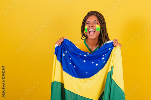 black woman young brazilian soccer fan. holding brazil flag, waving and celebrating.