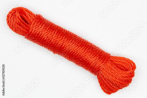 A coil of rope. Isolated. Large spool of red plastic cord on a white background. A long coil of kapron textured red cable. Durable nylon wire. Beautiful sea knot. Close-up. photo