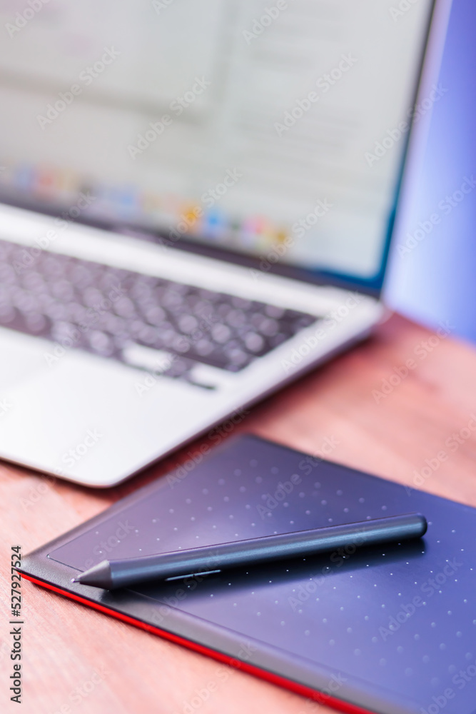 Graphic designer's workplace. Laptop and graphics tablet on a wooden table. Freelance work concept Graphic designer's workplace. Laptop and graphics tablet on a wooden table. Freelance work concept