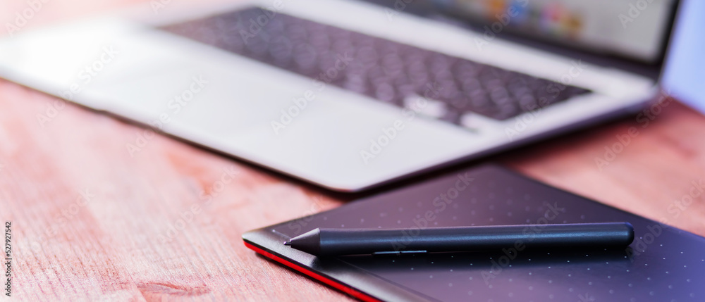 Graphic designer's workplace. Laptop and graphics tablet on a wooden table. Freelance work concept Graphic designer's workplace. Laptop and graphics tablet on a wooden table. Freelance work concept