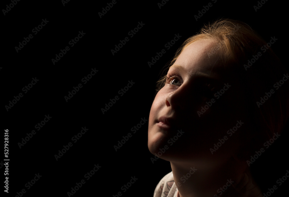 Young Caucasian girl looking upwards just away from the light with a very slight smile. Young Caucasian girl looking upwards just away from the light with a very slight smile.