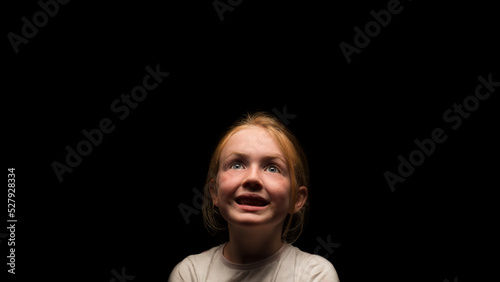 Young Caucasian girl looking upwards into the light with a smile.