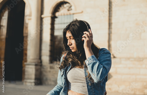 woman enjoying music with wireless headphones in an outdoor park at sunset. Concept of mental health, music and vacation.