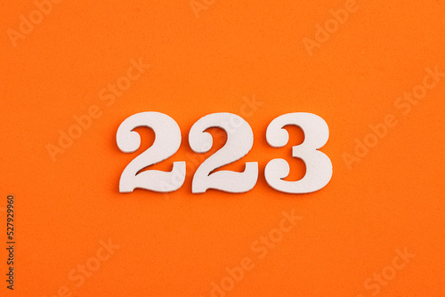 White wooden number 223 on eva rubber orange background photo