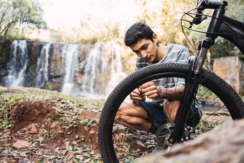 Man repairing detail of bicycle in woodland photo