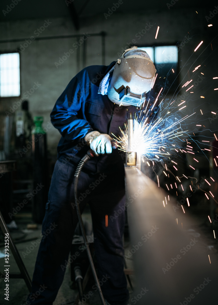 Professional welder in protective helmet in workshop Professional welder in protective helmet in workshop