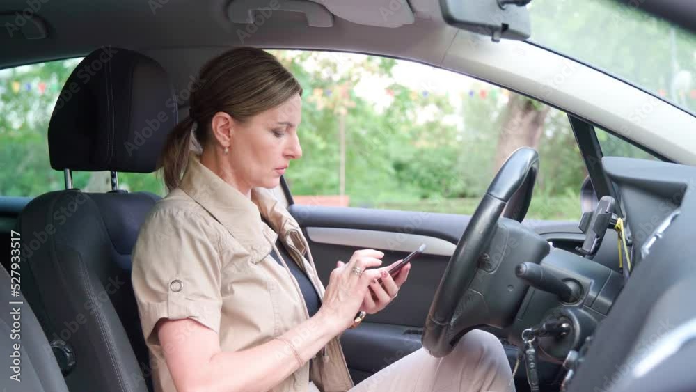 Female driver behind wheel of her car uses navigation program Female driver behind wheel of her car uses navigation program