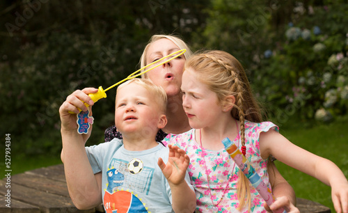 Caucasian family playing with bubbles in the park on a summers day.