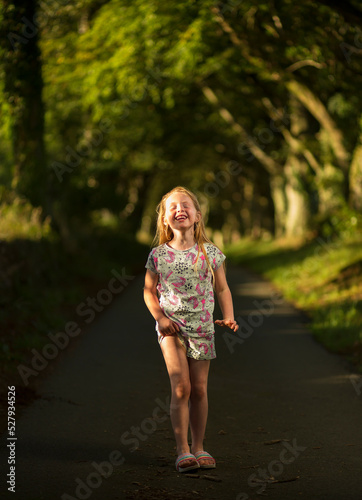 Young Caucasian female walking and laughing on a path in the countryside, a mixture of natural and flash light is used.