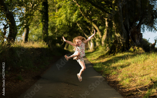 Young Caucasian female jumping on a path in the countryside, a mixture of flash and natural light used. © Carl