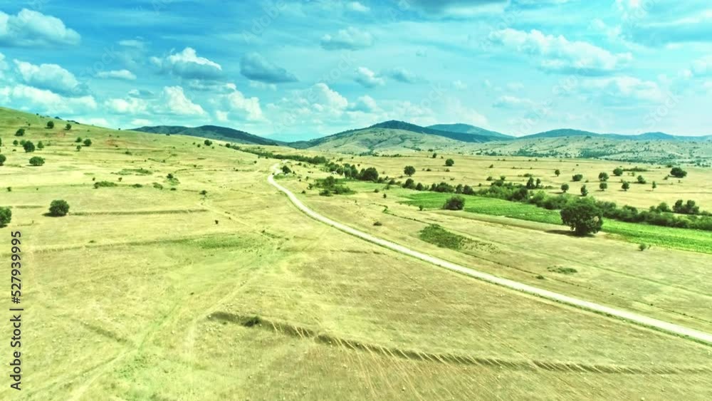 Beautiful nature, local curvy road across rolling land, sparse trees, impressive sky with clouds Beautiful nature, local curvy road across rolling land, sparse trees, impressive sky with clouds