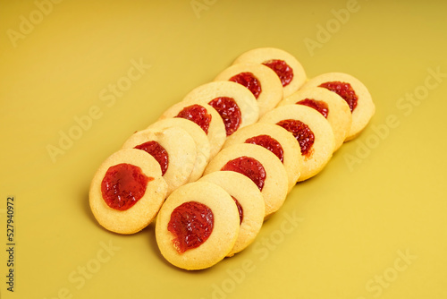Round sweet cookies with quince jam center on yellow background photo
