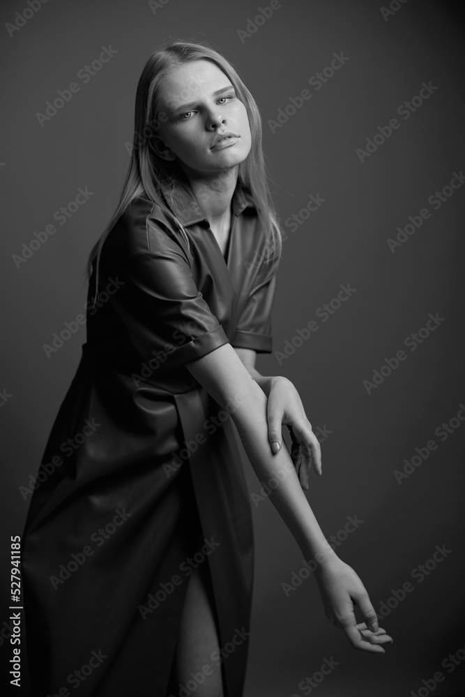 Gorgeous pretty confidence young blonde model in stylish leather brown palette dress trench coat posing isolated on olive green studio wall background. Expressive woman looks at camera. Fashion offer