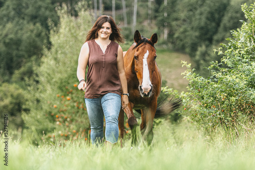 Portrait of a young woman interacting with her horse. Horsemanship concept: Bond between a female equestrian and her brown warmblood horse