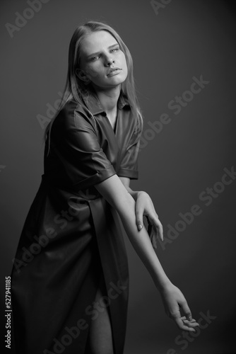 Gorgeous pretty confidence young blonde model in stylish leather brown palette dress trench coat posing isolated on olive green studio wall background. Expressive woman looks at camera. Fashion offer