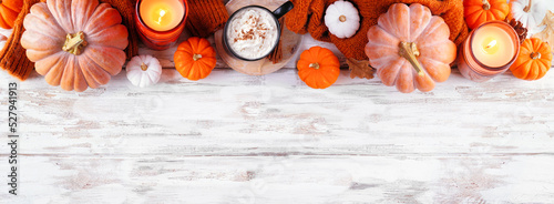 Cozy fall top border with pumpkins, leaves, sweater and pumpkin spice drink. Overhead view over a rustic white wood banner background. #527941913