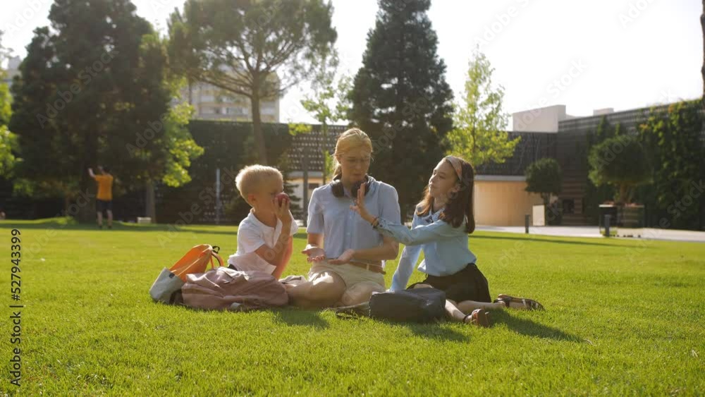 A schoolboy boy treats his friends with red apples on the lawn of the school yard. Lunch break between classes. A schoolboy boy treats his friends with red apples on the lawn of the school yard. Lunch break between classes.