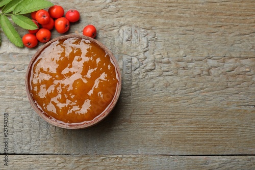 Delicious rowan jam and berries on wooden table, flat lay. Space for text