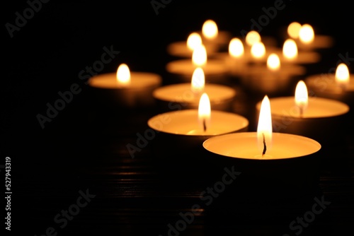 Burning candles and space for text on black background, closeup. Memory day photo