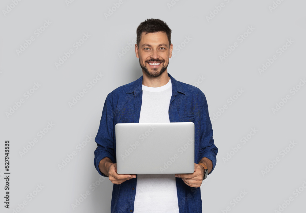 Smiling man with laptop on light grey background Smiling man with laptop on light grey background