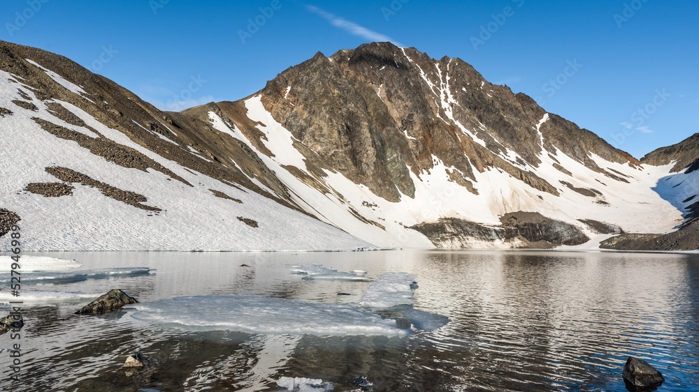 Mountain landscape in northern Canada with blue sky background and large ice chunks. 