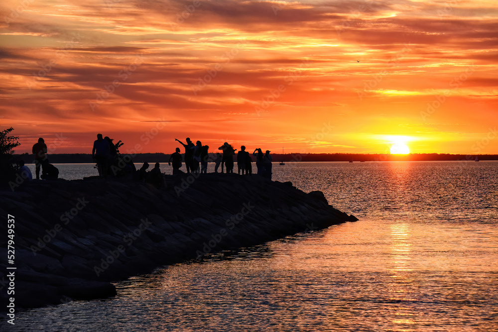 People gather on breakwater to watch sunset