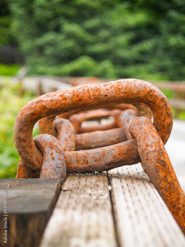 Large heavy rusty chain links hanging over fence Large heavy rusty chain links hanging over fence