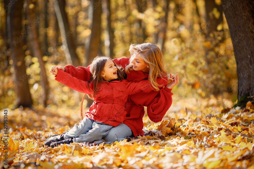 Mother and daughter sitting on a blanket in autumn forest Mother and daughter sitting on a blanket in autumn forest