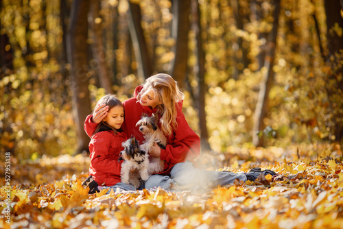 Mother and daughter sitting on a blanket in autumn forest with dogs