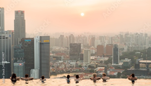 An afternoon at the infinity pool in singapore with sun setting in background over the buildings city skyline