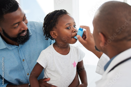 Fotografía Doctor helping a child patient with an asthma inhaler in his office at the medical clinic