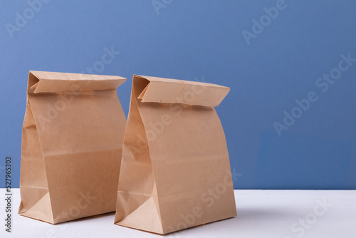 Close-up of brown paper lunch bags on table against blue background with copy space