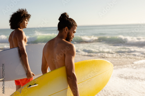 Multi-ethnic males holding surfboards on the beach #527965514