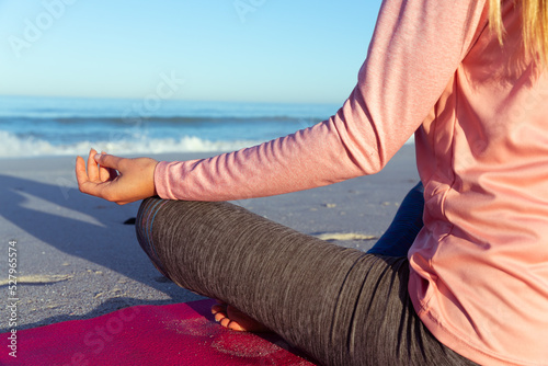 Caucasian woman practicing yoga seaside